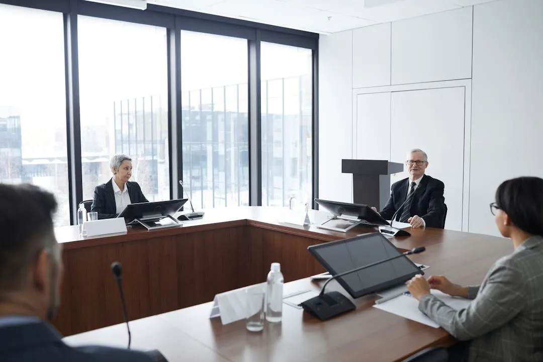 Executives in a modern boardroom meeting with tablets and presentation screens